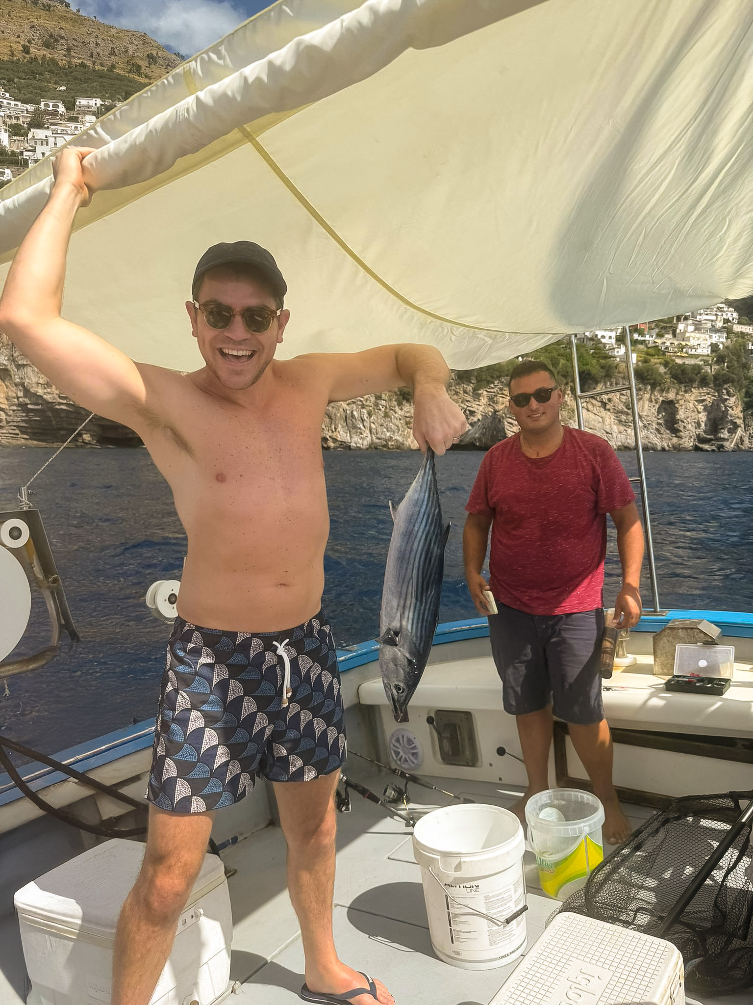 Man holding a freshly caught tuna during a fishing boat tour along the Amalfi Coast near Positano