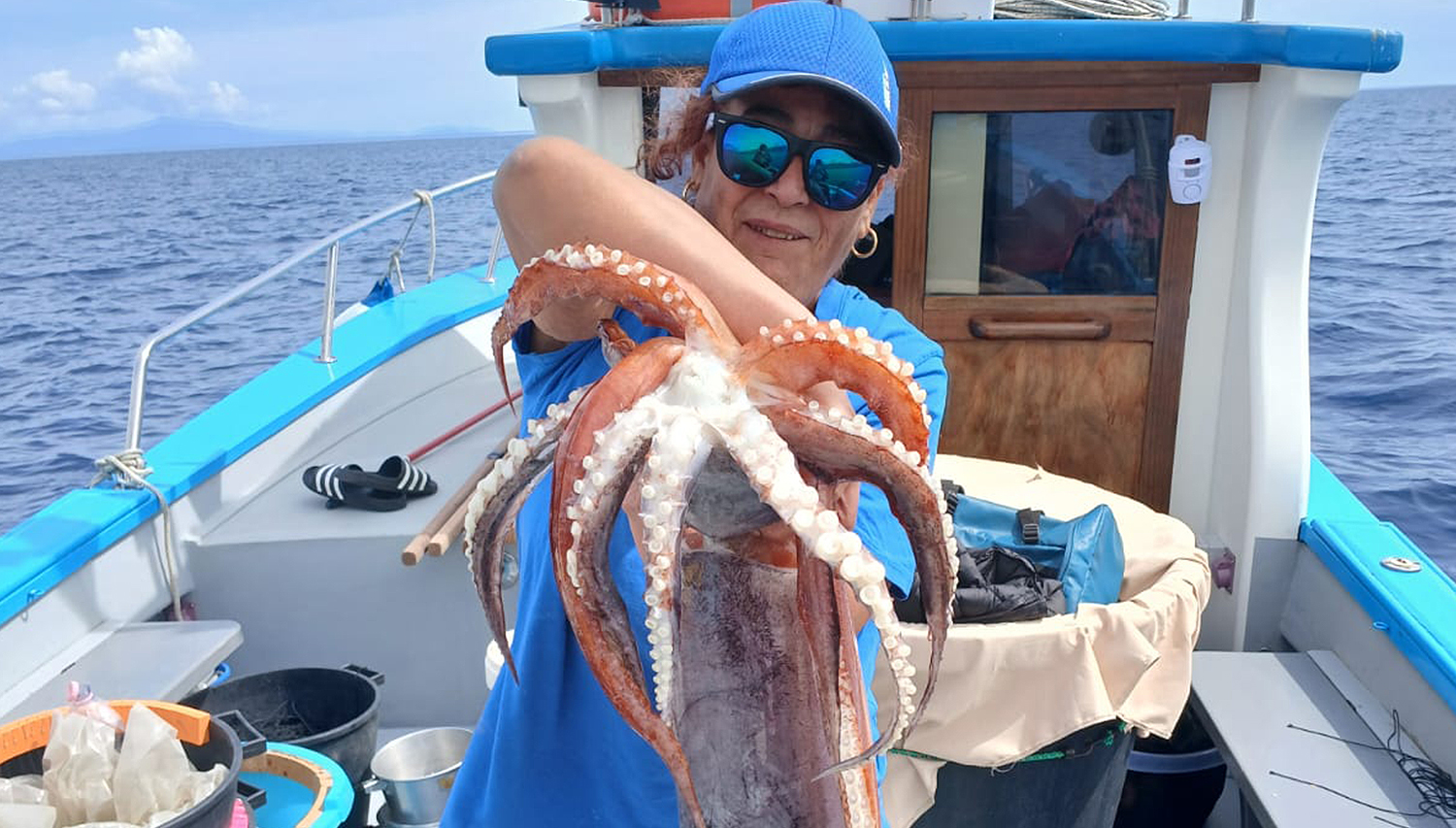 Woman proudly displaying a giant squid caught during a deep sea fishing tour on the Amalfi Coast