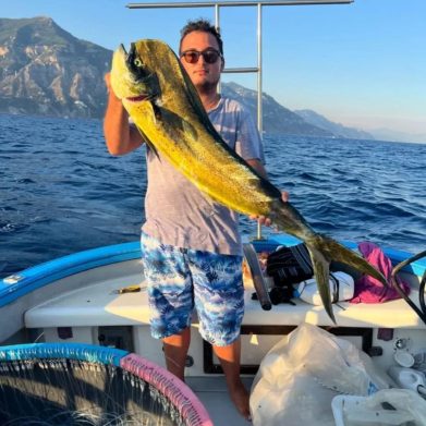 Young man holding a large mahi mahi caught during a fishing trip on the Amalfi Coast